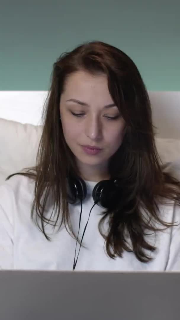 Colpo verticale Bella donna caucasica attraente con i capelli lunghi a letto che lavora su un computer portatile. — Video Stock