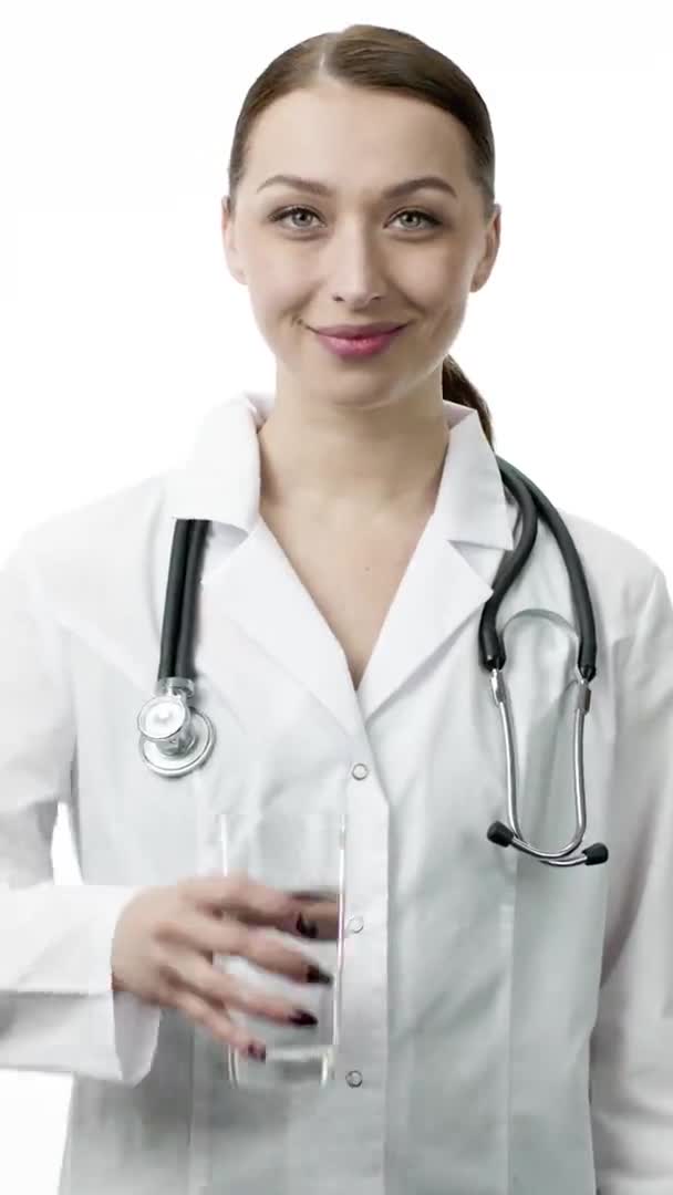 Молодая женщина врач держит стакан чистой воды и показывает, как знак с большим пальцем вверх — стоковое видео