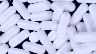 Dikey video beyaz antibiyotik kapsülleri siyah arkaplan üzerinde yalan söyler ve döner