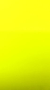 Dikey video. Bir damla su yavaş çekimde parlak sarı arka planda bir sıvının yüzeyine düşer.