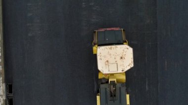 Dikey video. Sarı bir patika. Yeni sıcak asfaltı düzleştirmiş. Yeni bir yol yap. Arial İHA atışı.