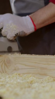 Katılımcının dikey çekim elleri atölyede ahşap boş elektrikli planör kullanıyor..