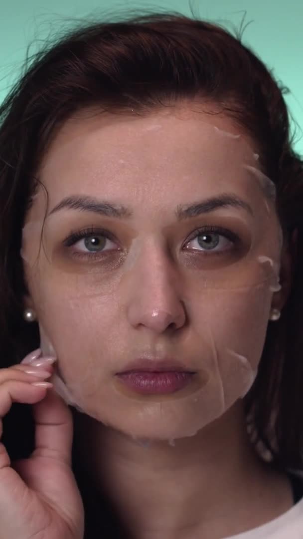 Plan vertical Belle femme au lit enlève un masque à base d'eau de son visage avec sa main — Video