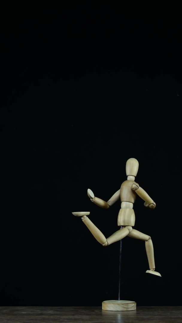 Vertikal video Stopmotion kör trä figur dummy i studio på svart bakgrund roterar med fryst rörelse — Stockvideo