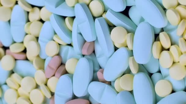 Vertikální video Mnoho multi-barevné modré a žluté léky antibiotika pilulky otáčet na stole — Stock video