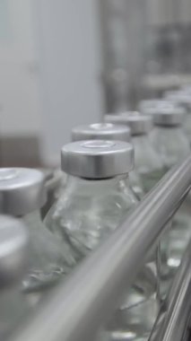 Tıbbi çözüm taşıyıcı hattındaki kauçuk ve alüminyum kapaklarla doldurulmuş ve mühürlenmiş dikey video cam şişeleri seçici odak noktasını kapat