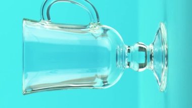 Dikey video 4K yakın plan. Stüdyodaki latte bardağı mavisi arka planda duran gazlı kola soğuk içecek içeceği.