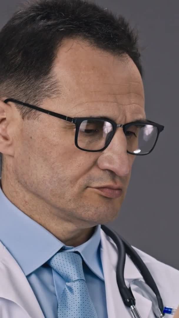 Вертикальний знімок Крупним планом серйозний лікар в медичній формі пише діагноз пацієнта на кишені — стокове відео