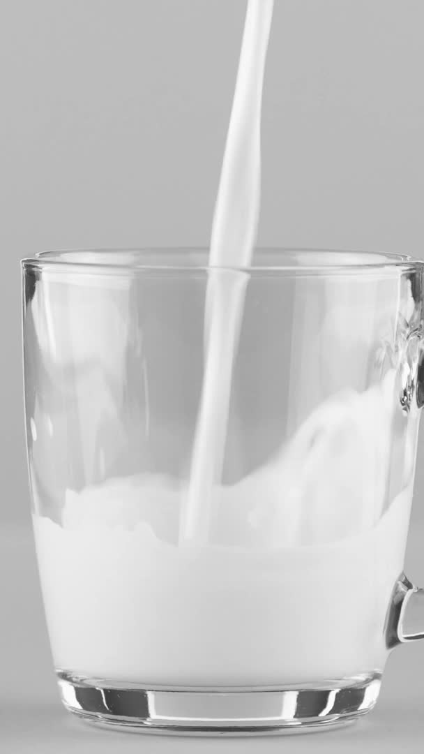 Függőleges videó Milk öntő üveg bögre közeli elszigetelt világosszürke háttér — Stock videók