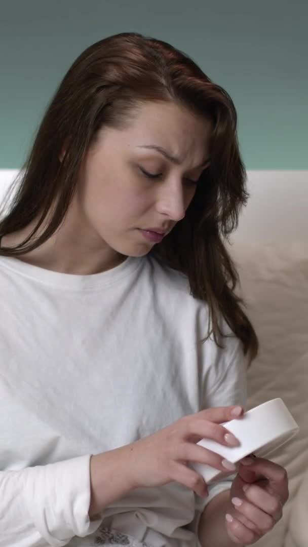 Vertical shot Hermosa chica caucásica con el pelo largo en la cama establece reloj despertador y se va a la cama — Vídeo de stock