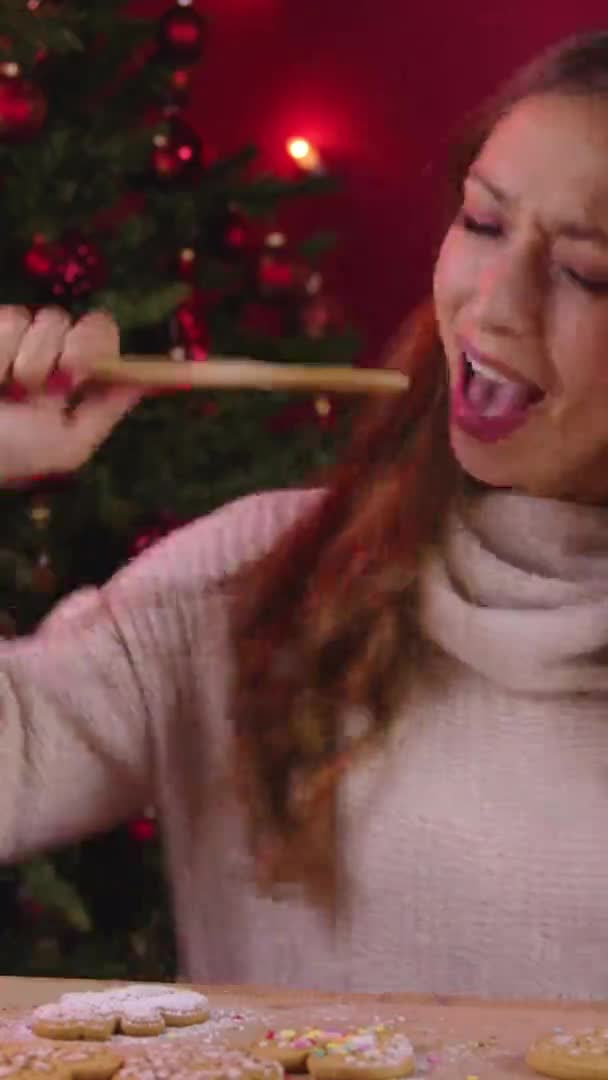 Vertikale Aufnahme Nettes langhaariges Mädchen singt Dekoration handgemachte Lebkuchen auf Weihnachtsdekoration — Stockvideo