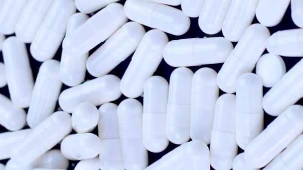 Verticale video Witte antivirale capsules liggen en draaien op een zwarte achtergrond — Stockvideo