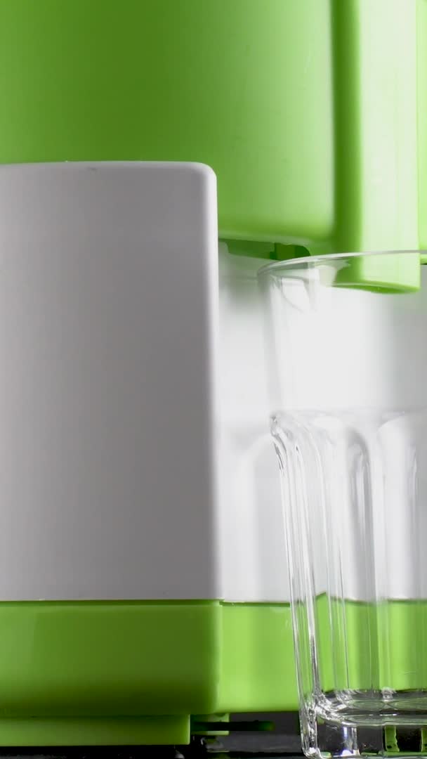 Vertikales Video Frisch gepresster Orangensaft wird aus einer Saftpresse in einen Glasbecher gegossen — Stockvideo