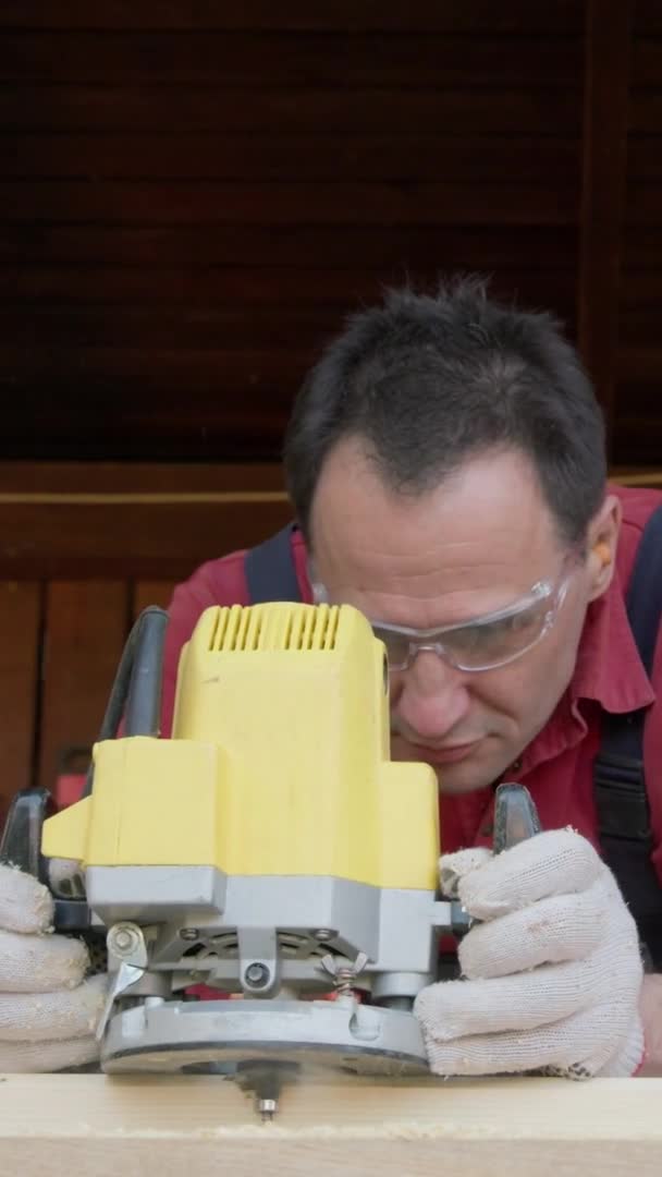 Plan vertical Travailleur du bois découpe poutre en bois avec fraiseuse dans l'atelier de menuiserie bricolage — Video