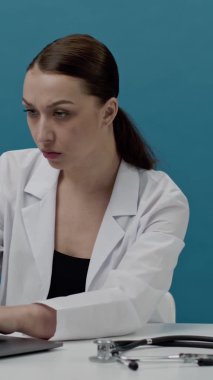 Dikey çekim. Odaklanmış doktor laptopta çalışıyor. Tıbbi kayıtları dolduruyor.