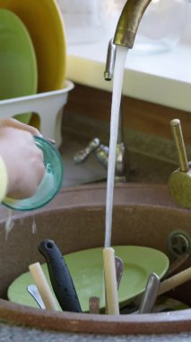 Dikey çekim ev hanımı kirli cam bardağı deterjanla yıkadı..