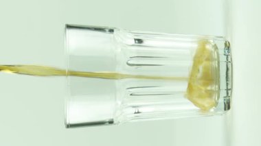 Dikey video Kola, beyaz arkaplanda izole edilmiş kabarcıklar ve köpüklerle dolu bir bardağa dökülür.