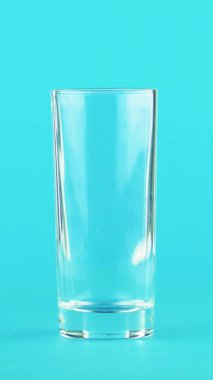 Dikey video 4K yakın çekim meyve portakalı multifruit suyu soğuk içecek Stüdyoda düşük cam mavi arka planda poz