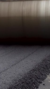 Dikey video. Büyük sarı buharlı silindir. Sıcak asfalt düzleştirilmiş. Yeni bir yol inşa eder