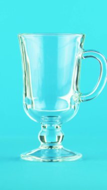 Dikey video 4K yakın çekim meyve portakalı multifruit suyu soğuk içecek Stüdyoda latte cam bardak kupa mavi arka planda podlanan