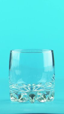 Dikey video 4K yakın plan. Stüdyodaki küçük cam mavi arka planda duran gazlı kola soğuk içecek.