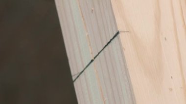 Dikey çekim İşçisi kalemi işaretliyor ve değirmen makinesiyle tahtayı kesiyor.