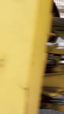 Dikey video Paver asfalt takıyor. Ağır ekipmanlar sıcak asfaltı dümdüz ediyor. Yol buharı.