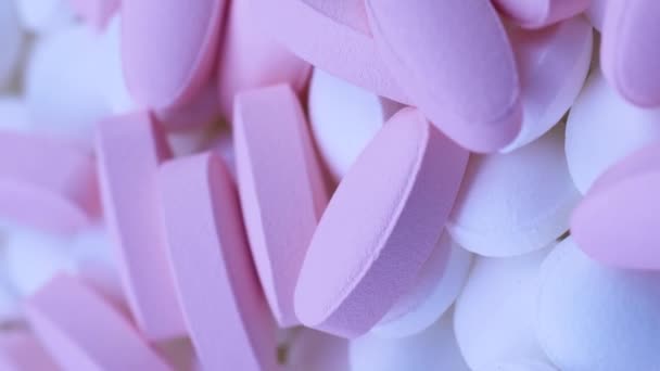 Vertikale Video Pink ovale Pillen liegen mit kleinen weißen runden Medikamenten. Rotation aus nächster Nähe