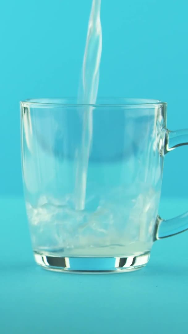 Verticale video 4K close-up shot van gele citroen bruisende limonade soda koude drank drinken arm in glas mok met afgeronde handvat blauwe achtergrond in studio — Stockvideo