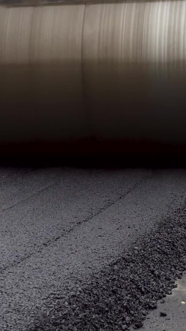 Függőleges videó Egy nagy sárga gőzhenger lelapítja a forró aszfaltot. Új utat épít. — Stock videók
