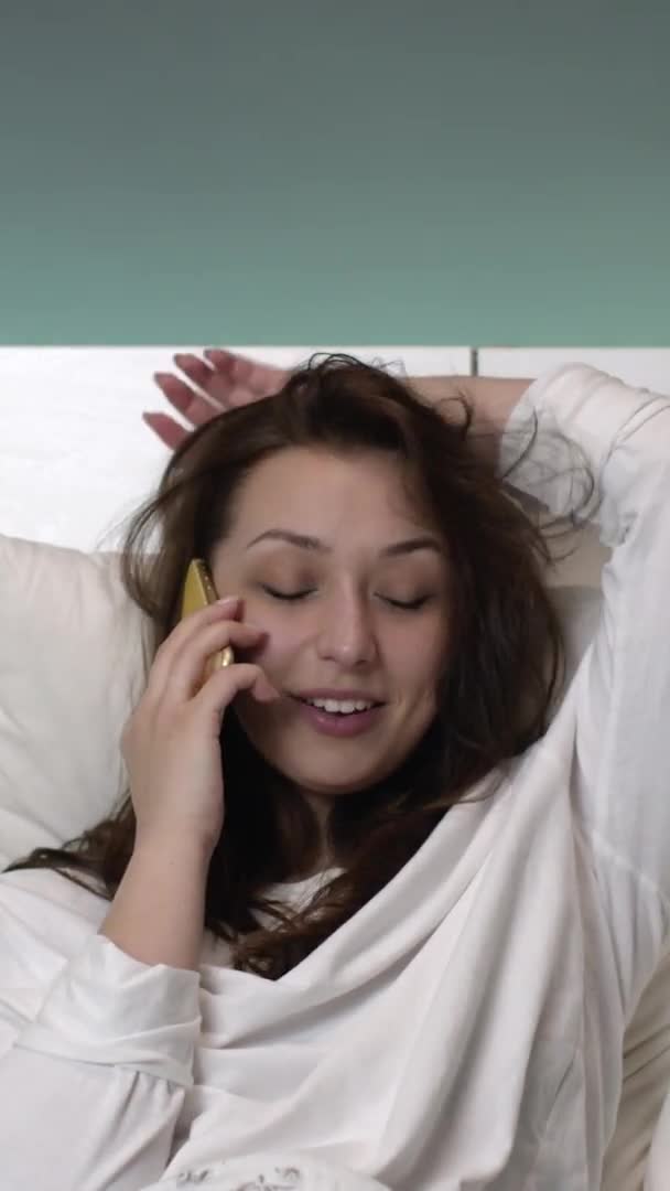 Tiro vertical feliz sexy marrom cabelo menina em branco nightie se comunica antes de dormir — Vídeo de Stock