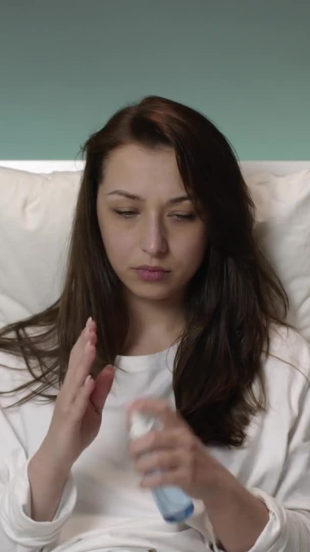 Vertikální výstřel Děsivé mladé dívky v pyžamu v posteli doma postřikuje antiseptické všude. — Stock video
