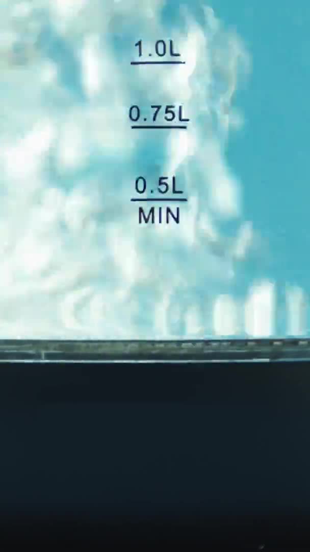 Vertikale Video Wasserkocher mit Glaswänden. Siedend. Blauer Hintergrund. Rostfreier Boden — Stockvideo