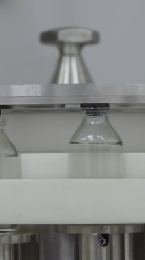 Dikey cam şişeler tıbbî çözüm konveyör hattına plastik kapaklarla doldurulmuş ve mühürlenmiş.