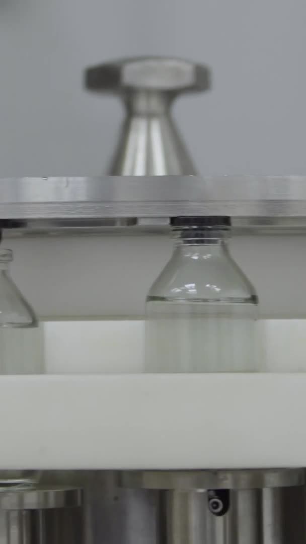 Vertical video glass bottles filled and sealed with rubber caps on a medical solution conveyor line close up — Stock Video