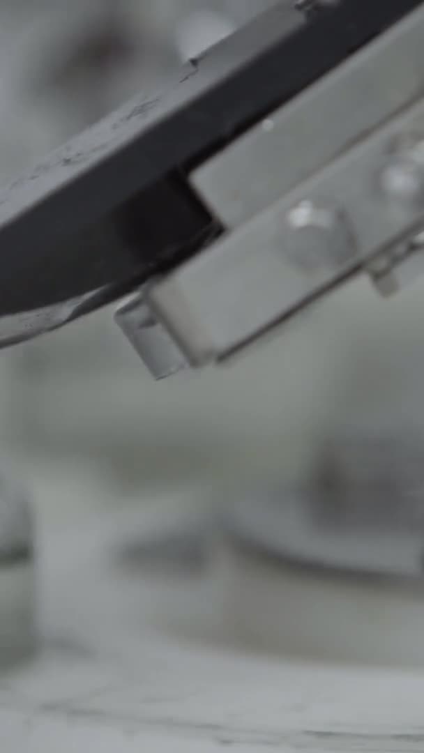 Вертикальное видео стеклянные бутылки заполнены и запечатаны резиновыми колпачками на медицинском решении конвейерной линии алюминиевой крышки упаковочной секции крупным выборочным фокусом — стоковое видео