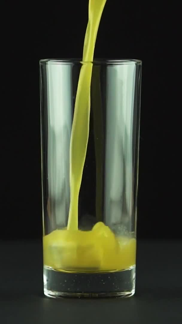 Vertikální video Šťáva nalévání do skla izolované na černém pozadí zpomalený pohyb — Stock video