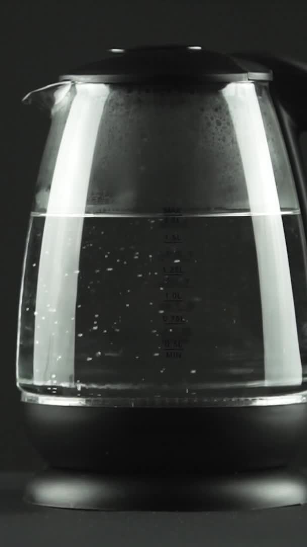 Vidéo verticale Dans une bouilloire électrique avec des murs en verre transparent, l'eau bout. Concept. Plan studio — Video