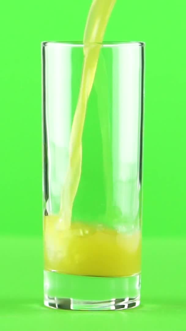 Vidéo verticale Jus versé dans du verre isolé sur fond vert clair ralenti — Video