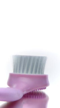 Dikey video Pembe yüz temizleme fırçası beyaz arka planda dönüyor. Cilt masajı aracı