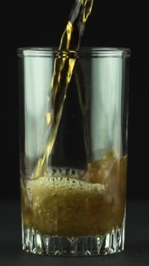 Dikey video Kola, siyah arkaplanda izole edilmiş kabarcıklar ve köpüklerle dolu bardağa dökülür.