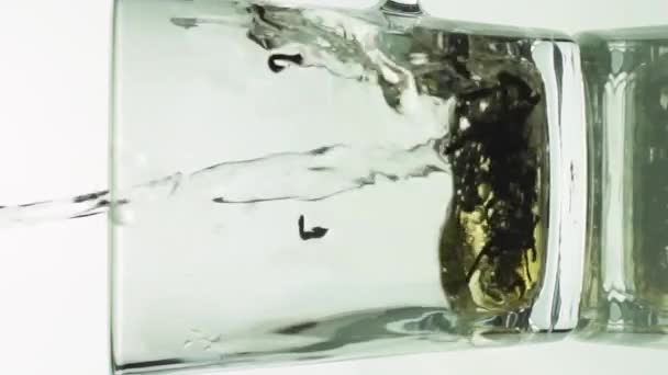 Vertikální video černé čajové částice nalévající se do skleněného průhledného hrnku a naplněné vroucí vodou vařit čaj izolované na bílém pozadí zpomalený pohyb zblízka — Stock video