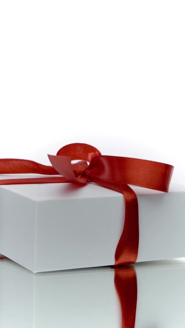Vídeo vertical Hermosa caja de regalo blanca con arco rojo girando aislado sobre fondo blanco — Vídeos de Stock
