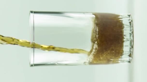 Verticale video Cola wordt gegoten in glas vol bellen en schuim geïsoleerd op witte achtergrond slow motion — Stockvideo