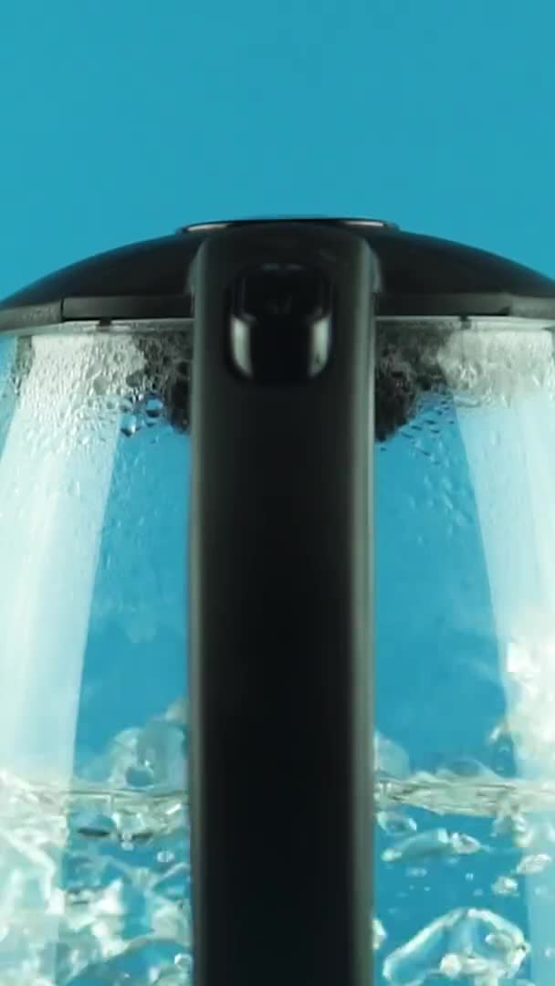Verticale video Een waterkoker met transparante wanden. Proces van koken. Blauwe achtergrond — Stockvideo