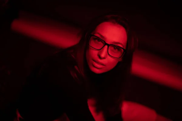 Retrato de sensual hermosa mujer en gafas posando en estudio oscuro luz roja — Foto de Stock