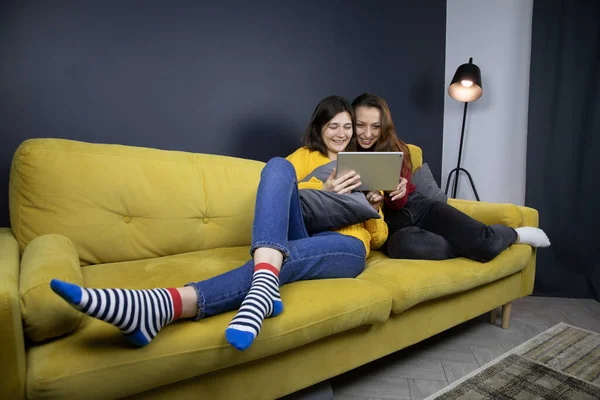 Dos chicas guapas ríen viendo comedia o videos divertidos de youtube en la tableta — Foto de Stock