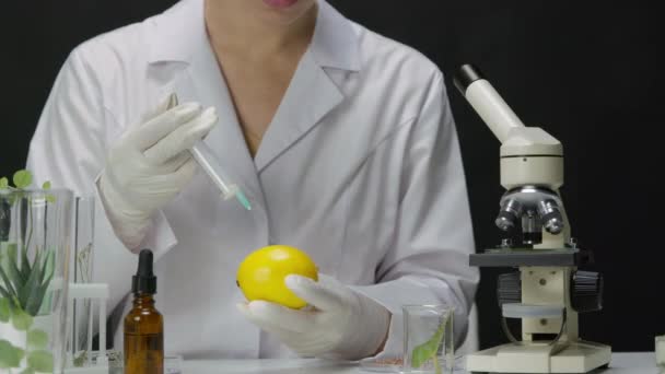 Vrouwelijke lab technicus in handschoenen het verkennen van citroen fruit door het injecteren van chemicaliën — Stockvideo