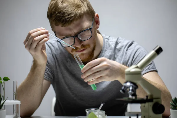 Szakállas biológus szemüvegben végez kémiai kísérletet zöld reagenssel — Stock Fotó