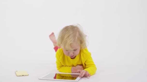 Urocza, skupiona dziewczynka leżąca na podłodze grająca w aplikacje na smartfonie — Wideo stockowe